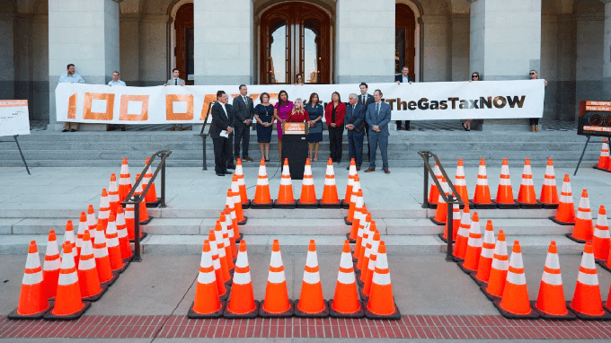 Republican lawmakers stand outside the California Capitol behind traffic cones creating the numeral "100."