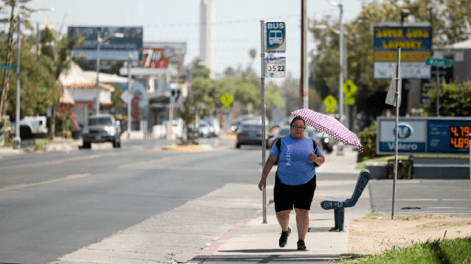 Image caption: A Fresno resident uses an umbrella to shield herself from the sun on Aug. 30, 2022, as a heat wave descended over California.