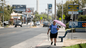 A Fresno resident uses an umbrella to shield herself from the sun on Aug. 30, 2022, as a heat wave descended over California.