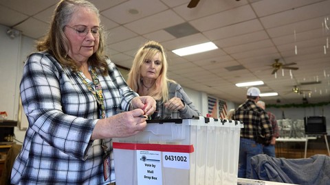 Poll workers Twyla Carpenter, left, and Regina Jasperse inspect the lock on a mail ballot drop box at a polling station at the American Legion in Shasta County on Nov. 7, 2023.