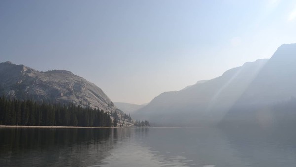 An image from September 2020 of Lake Tenaya in Yosemite National Park, with sunlight and shadows cast in the wildfire smoke hanging over the lake water.