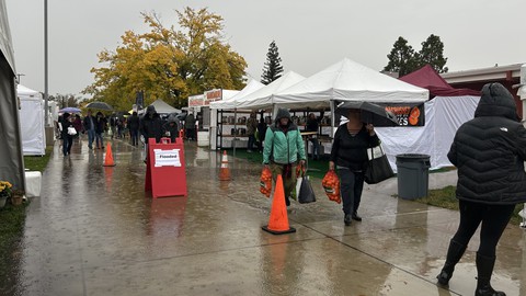 Image caption: Shoppers with their bags of mandarins avoid the flooded part of the sidewalk during the first day of the Mountain Mandarin Festival. The annual event is being held this year @the Grounds in Roseville, which received a significant dose of rain Friday.