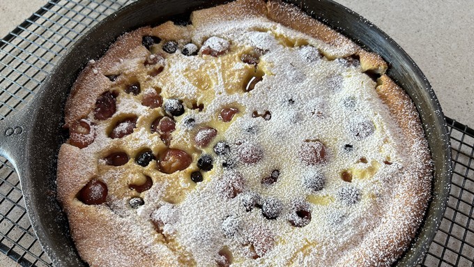 A sprinkling of confectioner's sugar tops this puffy ricotta pancake packed with cherries and blueberries.