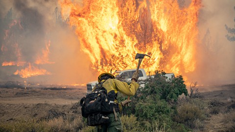 Image caption: A firefighter battles the Dixie Fighter, a massive blaze started by PG&E equipment.