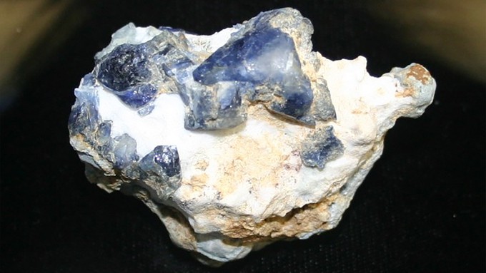 Image caption: Blue benitoite crystals on white natrolite, mined in San Benito County.