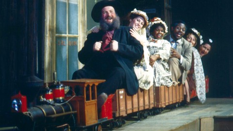 Image caption: Founding artistic director Robert Kelley (front of train) in TheatreWorks’ 1981 production of “Merry Wives of Windsor.”