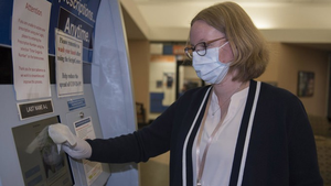 Jacqueline Bradford, an office assistant at Travis Air Force Base, disinfects a kiosk at a testing site in March. The state promises to be delivering 10,000 tests per day by the end of April.