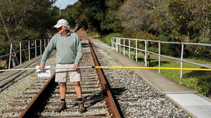 Miles Reiter, an opponent of rail and a board member for Greenway, walks the railroad tracks with a pole to show the width of the corridor.