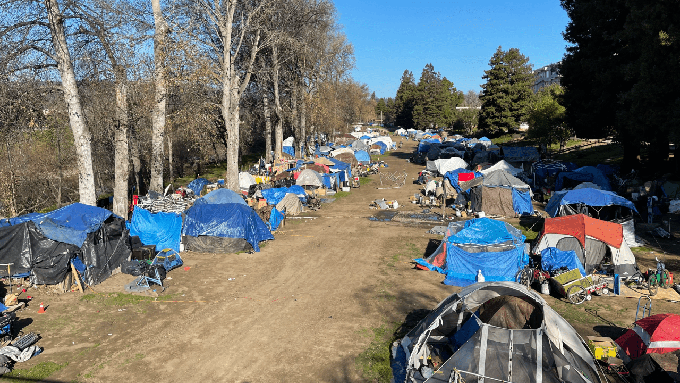 Image caption: A city-sanctioned homeless encampment directly adjacent to county government offices and across the San Lorenzo River from the heart of downtown Santa Cruz.