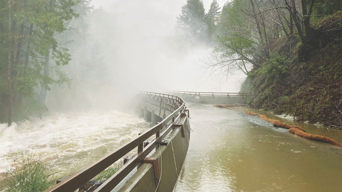 Image caption: Water spray covers the bridge over the Newell Creek Spillway.