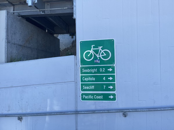 A sign at the end of Pacific Street by the boardwalk, at the base of the ramp up to the span over the San Lorenzo River.  
The sign indicates distance at the point in the rail trail to various destinations.