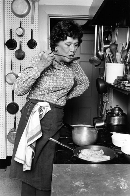 Julia Child tasting a dish while cooking