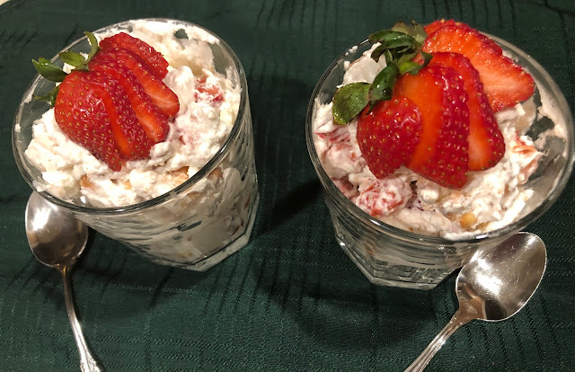 Two clear glass filled with cream and strawberries