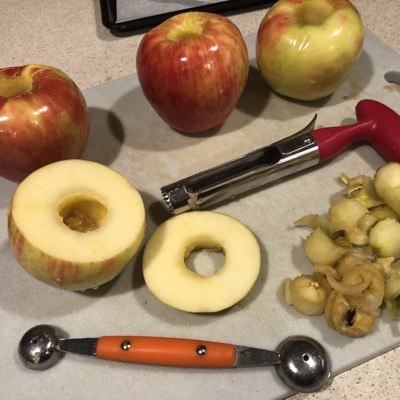 One cored apple and 3 others not yet cored, with tools