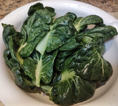 Washed bok choy leaves in a white colander