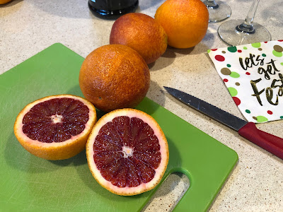 Blood orange cut in half on green cutting board