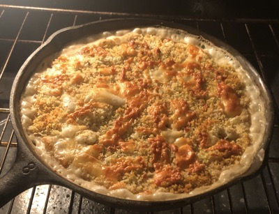 Bubbling casserole in a cast iron pan on an oven rack
