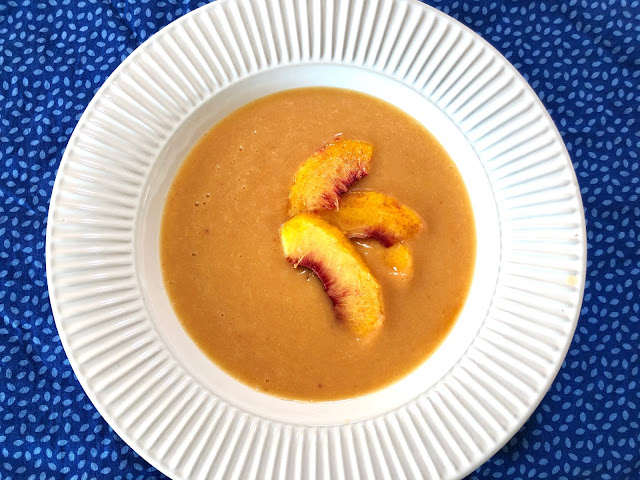 Peach soup in a white bowl on a blue background