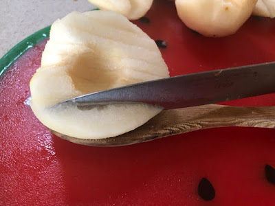 Half a pear being cut with a knife