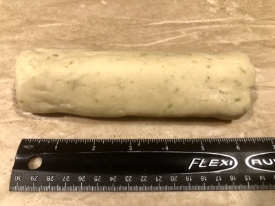 A log of dough and a black ruler showing it's 6 inches long