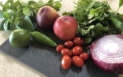 Onion, cilantro, herbs, tomatoes and nectarines on a cutting board
