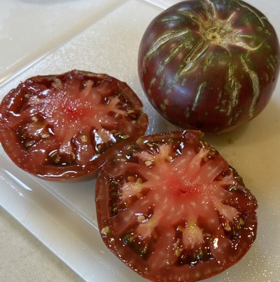 Two dark tomatoes, one cut in half