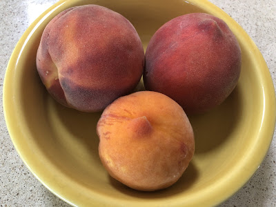 Three peaches in a yellow bowl