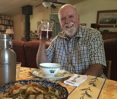 Bearded older man at table with glass of beer
