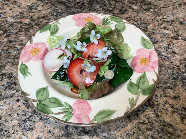 Plate with strawberries, violets, lettuce and radishes