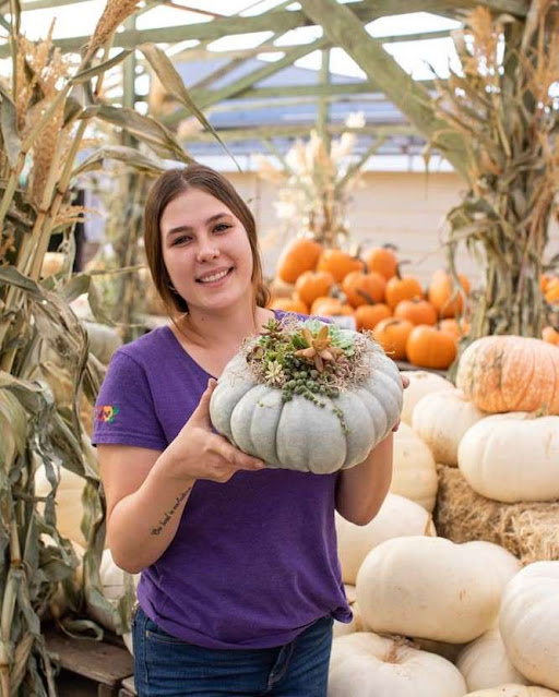 woman holding pumpkin with succulents
