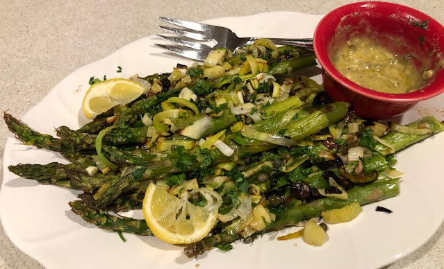 White plate with green asparagus and red bowl with mustard sauce