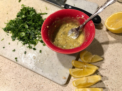 Mustard sauce in a red bowl, lemon slices and parsley