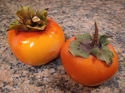 two flat persimmons on a cutting board