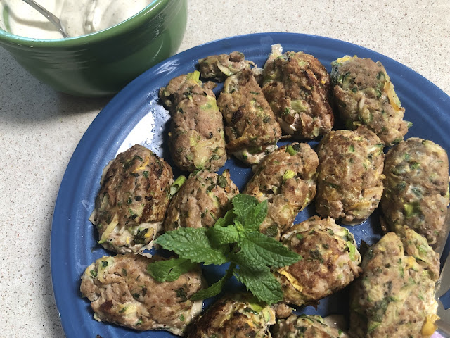 Turkey meatballs on a blue plate with yogurt sauce in a bowl