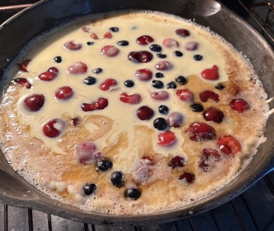 Pan with pancake batter and fruit in oven