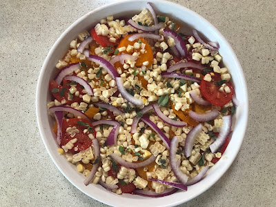 White dish with tomatoes, corn and red onion