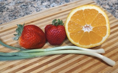 Salsa ingredients including strawberries and half an orange