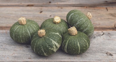 5 small green kabocha squash on a wooden bench