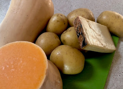Potatoes, squash, block of cheese, green cutting board