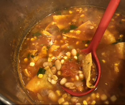 Tortilla soup being stirred in a large pot