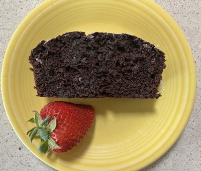 Chocolate zucchini bread and a strawberry on a yellow plate