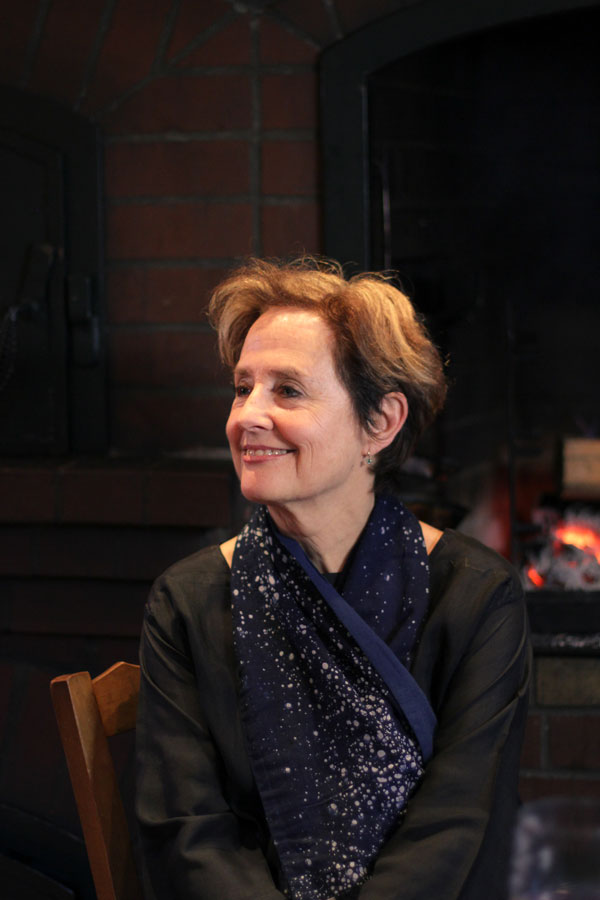 Alice Waters in a darkened room with an oven glowing in the background