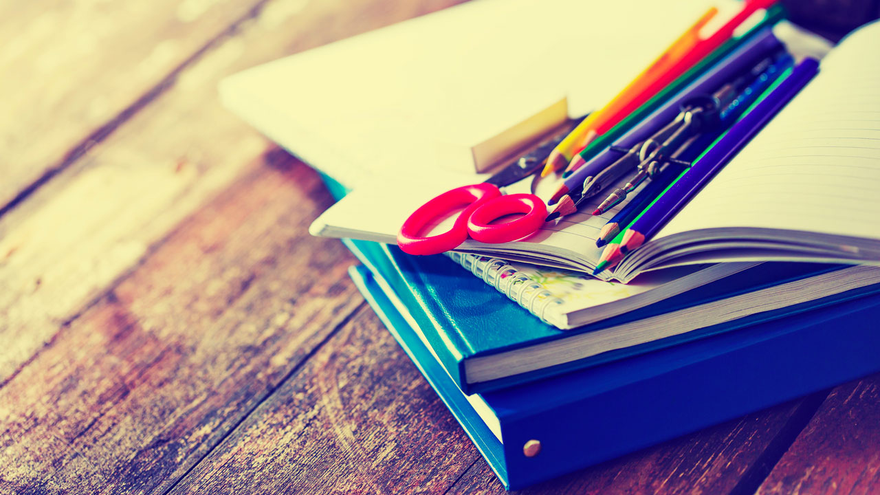 Stack of school supplies on a wooden desk