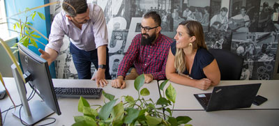 Three people at a desk looking at computer screen