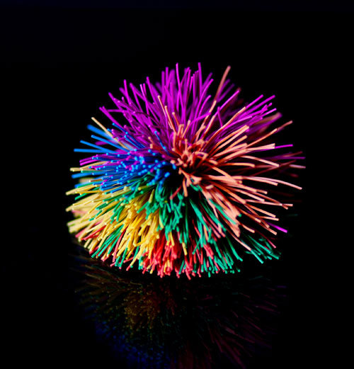 Brightly colored Koosh ball on a black background